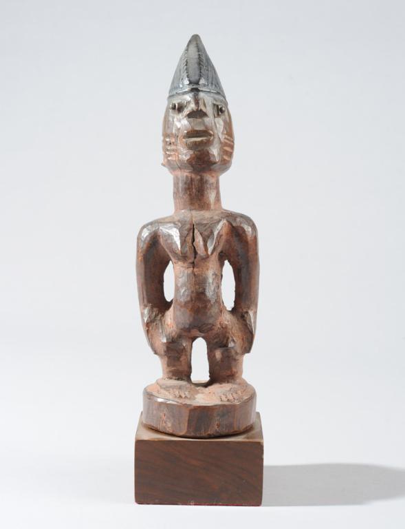 Yoruba Ibeji Twin Figure: Female figure with peaked coiffure, the slightly bulging eyes enhanced by nailheads, with short, broad nose above parted lips, with parallel scarification lines on each cheek and low-set, c-shaped ear
