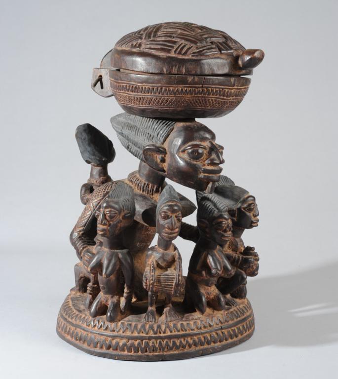 Yoruba "Agere Ifa" Divination Bowl: Elaborate agere ifa vessel with multiple figures, part of a Yoruba diviner's ensemble, in this case carved as a lidded basket balanced on the head of a fertile young woman with large, ridged coiffure,