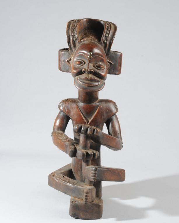 Chokwe Chibinda Ilunga Ancestor: Carved wood figure of Chibinda Ilunga, ideal chief and noble ancestor of the Chokwe people. The figure sits cross legged with a serene expression, the palms of the hands facing one another and parted,
