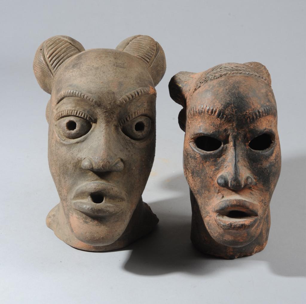 Two Nok Style Terracotta Heads: Pottery heads, their hair elaborately arranged in four orbs, made in the style of the ancient Nok culture terracotta figures found throughout Nigeria. Smaller appears to have repairs. Age unknown. Lar