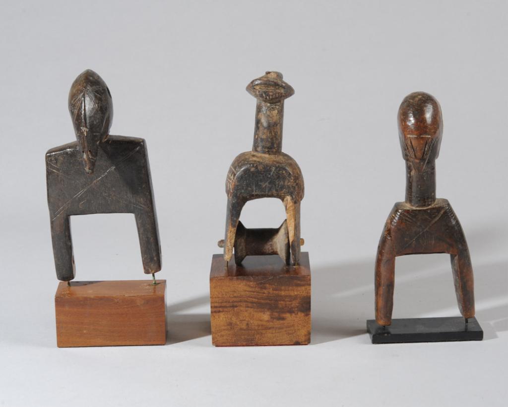 Three Senufo Heddle Pulleys: Ivory Coast. Two of avian form, the third with long neck, crested head, and relief carved geometric patterns on shoulders. All on custom gallery stands. Tallest pulley (height excluding stand,) approx