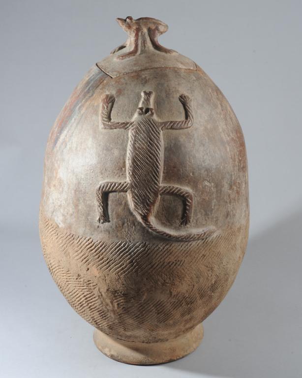 Gurunsi Terracotta Vessel, Burkina Faso: Ovoid lidded vessel, one side with relief image of a crocodile or lizard, the other side with the horned head of an antelope or similar creature. Zoomorphic lid finial. Approx. 25" H. Provenance: Esta