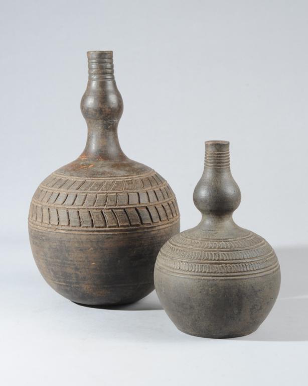 Two Banyoro Pottery Vessels, Uganda: Finely potted blackened terracotta bottles (ensumbi,) the long slender necks bulging slightly part way down to the rounded lower half. Incised linear decoration. Banyoro people, (also Bunyoro, Kitara,