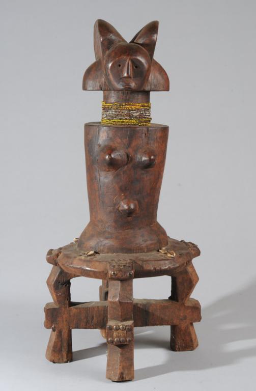Kwere / Zamoro Shrine Figure, Tanzania: Large Mwana Hiti type figure with typical split lobe hairstyle, minimalist facial features, and tapering columnar body with small breasts, on four legged stool. With beads, shells, scrap metal and tac