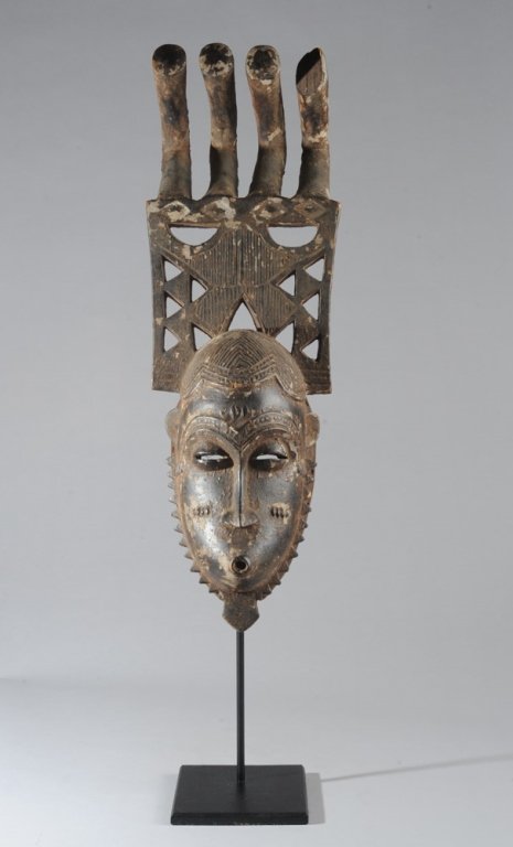 Tall Yaure Mask, Ivory Coast: With openwork and comb headdress towering above carefully arranged hair, the oval face with arched brows relief carved to match hairline, coffee bean eyes, lips pouted into a perfect circle below eleg