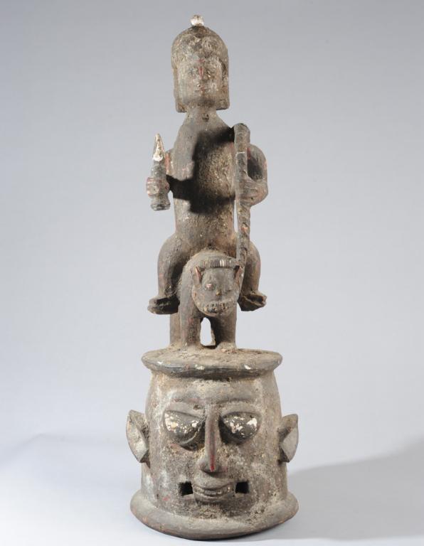 Yoruba Epa Helmet Mask, Nigeria: Double-faced helmet mask surmounted by armed equestrian figure. Encrusted surface, likely from ritual material, as such masks are cared for in shrines when not in use. Approx. 32" H. Provenance: Estat
