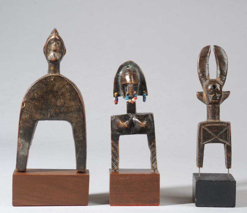 Three West African Heddle Pulleys: The tallest likely Kulango, Ivory Coast. The smallest a Bamana female figure with bead ornaments in nose and ears, Mali. The third a horned mask, likely a Senufo pulley, Ivory Coast. All on custom gal