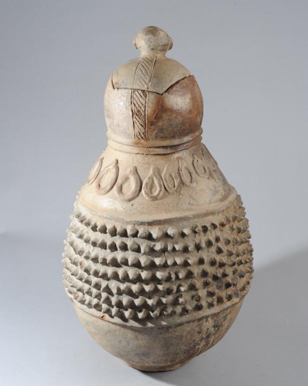 Lobi Terracotta Lidded Vessel: Double gourd shaped pot with applied studded central band below a line of applied teardrop shapes, the top section with incised lines. Fitted lid with large round finial in the form of a human head. D
