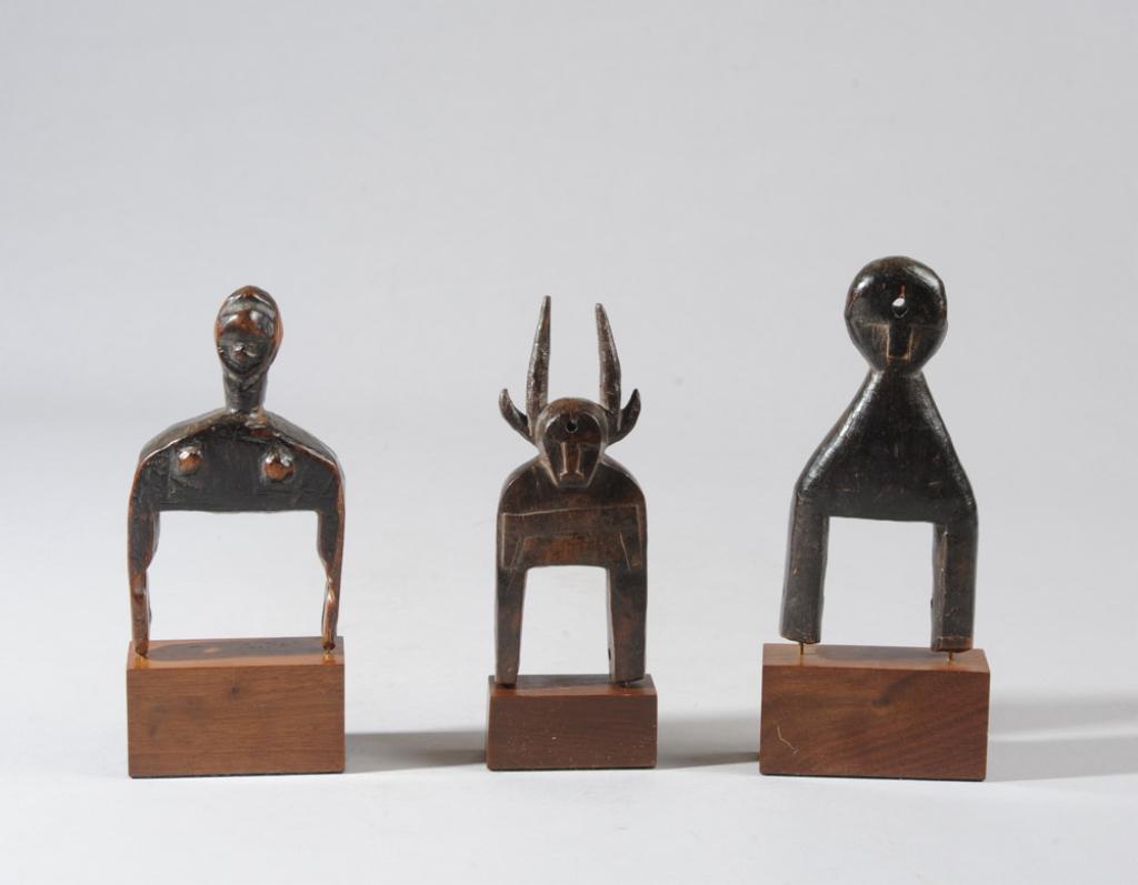 Three African Heddle Pulleys: Two anthropomorphic pulleys, one with a horned mask finial, all likely from Ivory Coast. All on custom gallery stands. Tallest (including stand) approx. 7" H. Provenance: Estate of Thomas McNemar, (19