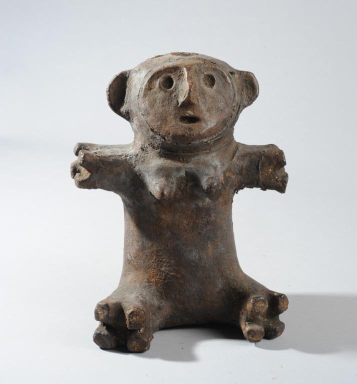 Zigua Terracotta Figure, Tanzania: Seated figure with truncated arms spread wide, the flattened facial plane with divots for eyes and mouth and a slender raised nose, and with large round ears. Round cavity in the top of the head. The 