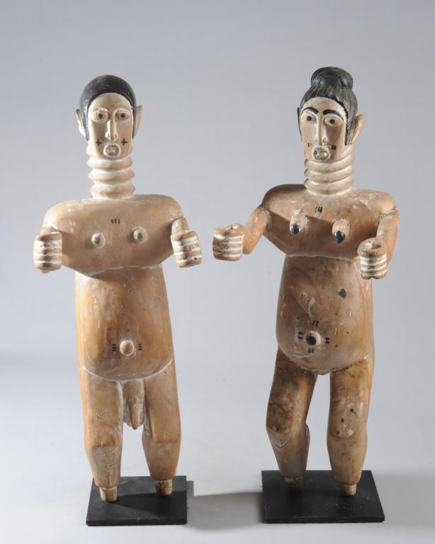Fante Male and Female Figures, Ghana: Standing figures with arms outstretched, hands positioned to grasp something. Whitened wood with black painted details. Legs end in pegs, with no feet. Both on custom gallery stands. Approx. 21 1/2" a