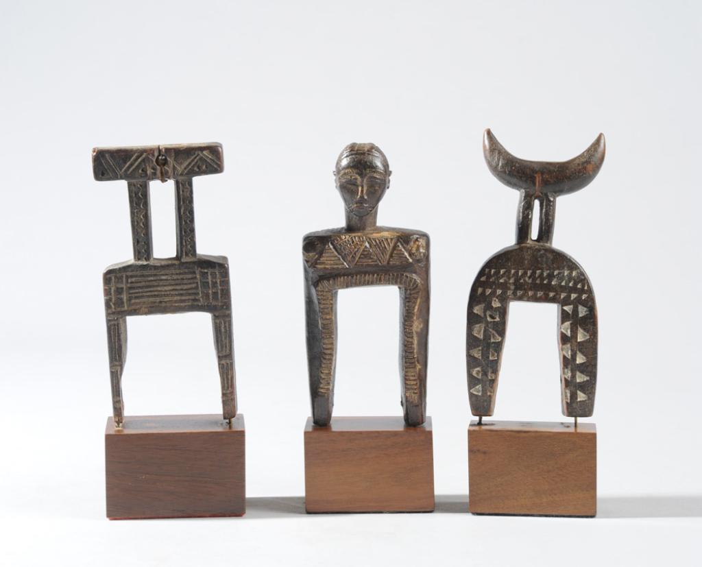 Three West African Heddle Pulleys: One likely Baule, the finial a finely carved face, the hair executed with delicacy and in remarkable detail. The shoulders each bear a mask head, identical but one is upside down. The other two pulley