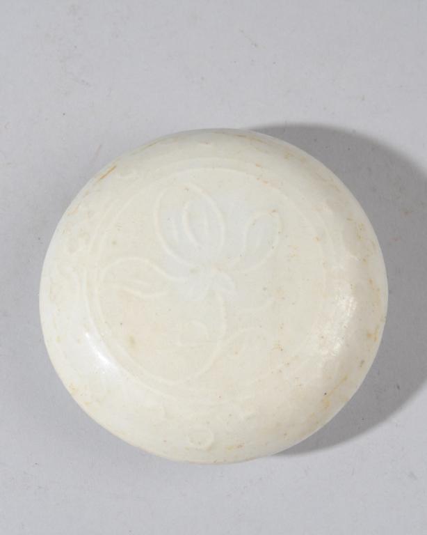 Chinese Song Dynasty Seal Paste Box: Small round white ware porcelain box and cover with raised design of lotus and scrolling vines beneath the slightly celadon tinted white glaze. Unglazed base. Approx. 3 3/4" D.