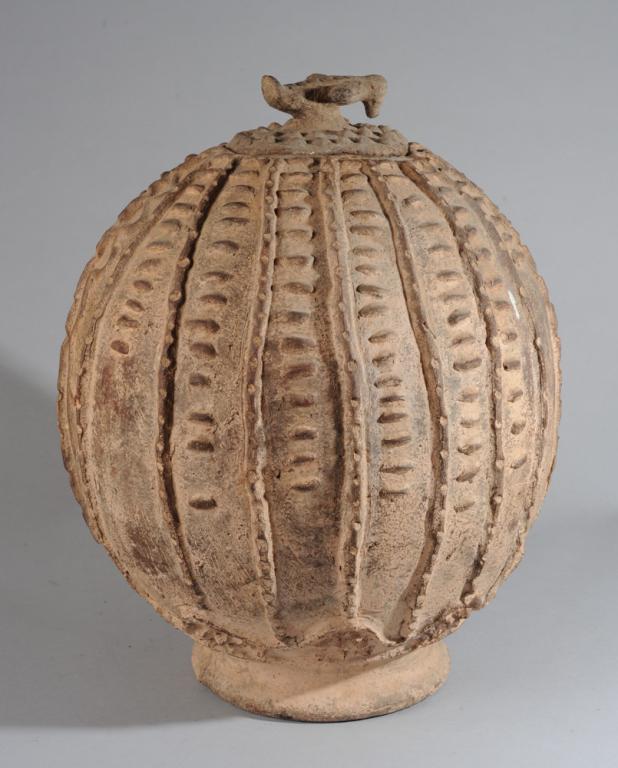 Lobi Lidded Pot: Ovoid terracotta pot on low pedestal foot with applied notched lines, dashes, dots, and snaking lines. Lid with bird finial. Lobi people, Burkina Faso. Approx. 21" H. Provenance: Estate of Thomas McNe
