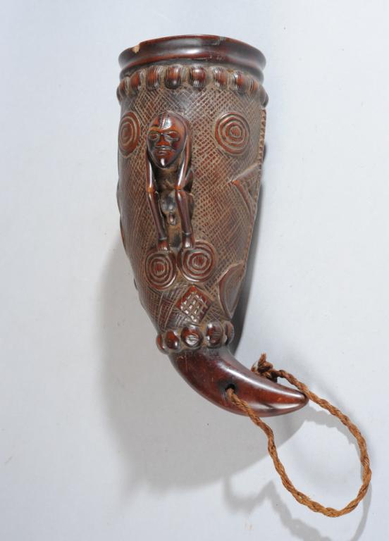 Kuba Carved Drinking Horn, D. R. Congo: With seated male figure carved in high relief, with geometric shapes and symbols and concentric circles carved in low relief against and incised ground. Hardwood or horn. Minor rim chip, crack. Approx