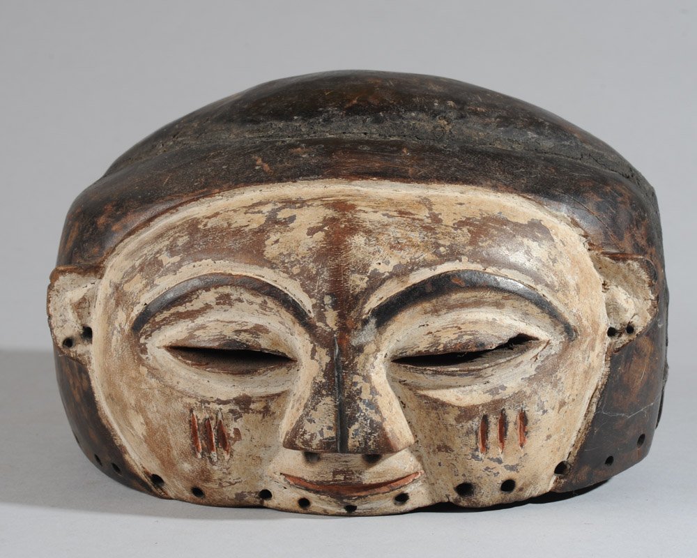 Suku Helmet Mask: Janiform mask with opposing wide, whitened faces, similar except that one is smiling with closed lips, the other has open mouth. Old tribal repairs/ reinforcements with cane, metal, and a mud like sub