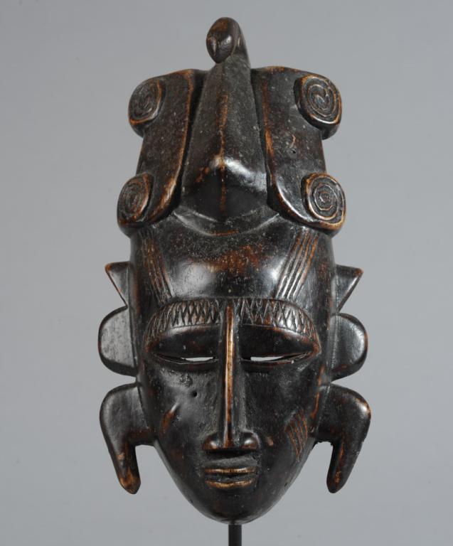 Ligbi Miniature or Passport Mask: Small mask with elaborate headdress, three projections on each side of the face, with closed eyes, long slender nose, pouting lips, with relief carved scarification on brow, temples and cheeks. Includ