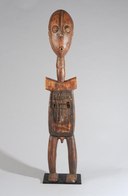 Large Zande Figural Sanza Mbira Thumb Piano: Musical instrument in the form of a standing male figure with elongated, oval head, long neck, the torso with metal keys set over a hollow area. The mask-like face with notched cranial ridge extending