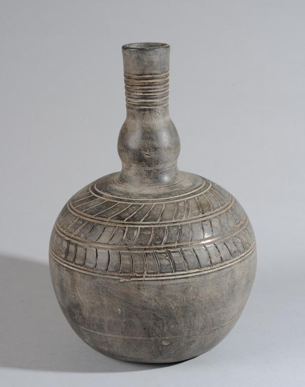 Nyoro Pottery 'Ensumbi' Vessel, Uganda: Bottle or gourd shaped vessel, the large round lower portion rising to long slender neck with swollen base, with incised linear patterns, dark burnished surface. approx. 15" H, 9 1/2" D. Provenance: E