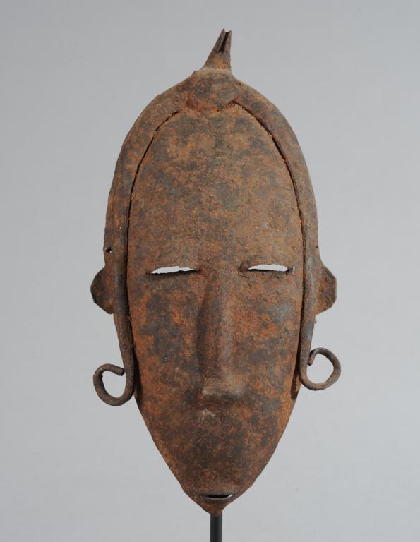 Bamana / Bambara Iron Mask, Mali: The oval face of a maiden with lowered eyes. Includes custom gallery stand. Mask, approx. 10" x 5". Provenance: Estate of Thomas McNemar, (1931-2020.) McNemar lived and collected throughout Central an