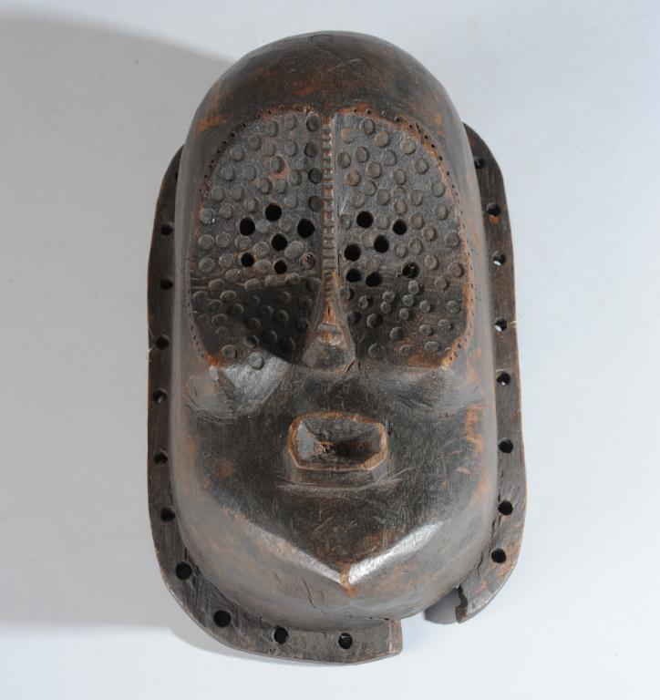 Lulua Mask: The large convex area of the eyes and cheeks with many perforations, the nose notched along its length, the lips protruding above the pointed chin. Loss to area of perforated edge below chin. Minor ag