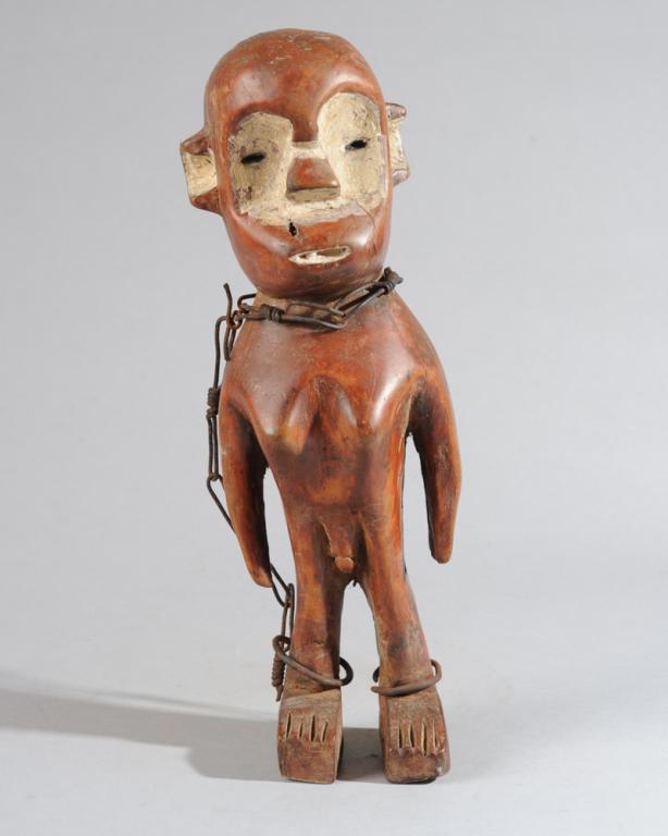 Fang Figure, Angola: Standing carved wood figure, the large head suggestive of a monkey with its small round ears and lipless, projecting mouth. The somewhat anthropomorphic body has prominent breasts, male genitalia and 