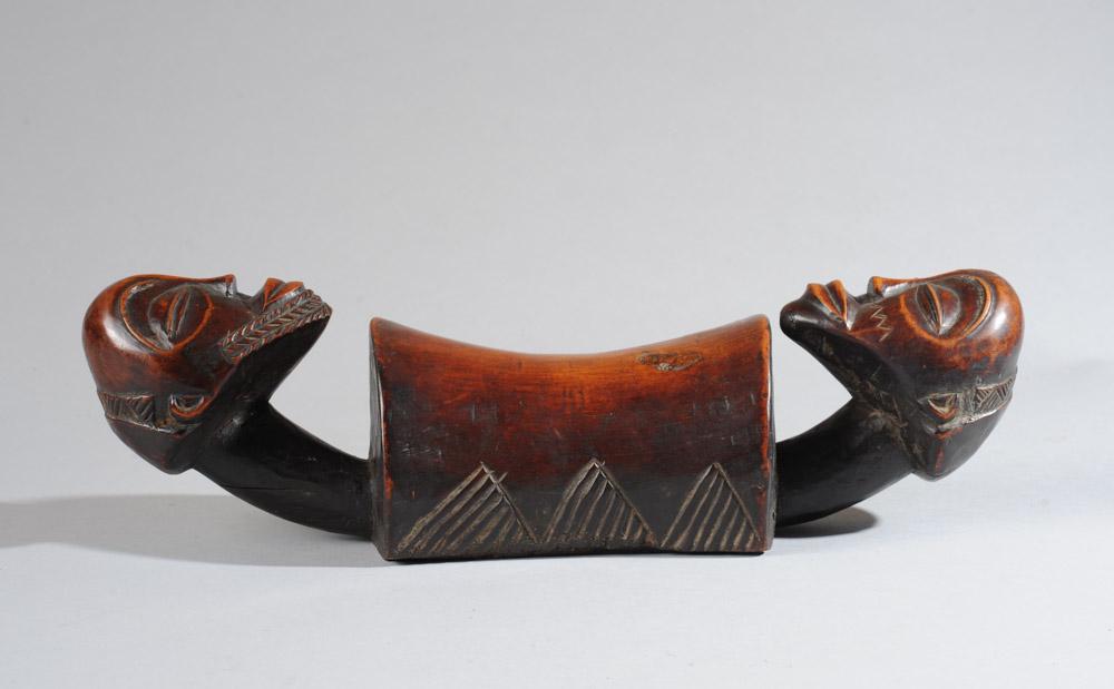 Luba Headrest: Finely carved headrest with a male and female head at each end, the faces with high arched brows over closed eyes, the male with plaited beard, the female with facial scarification, both with elegant 