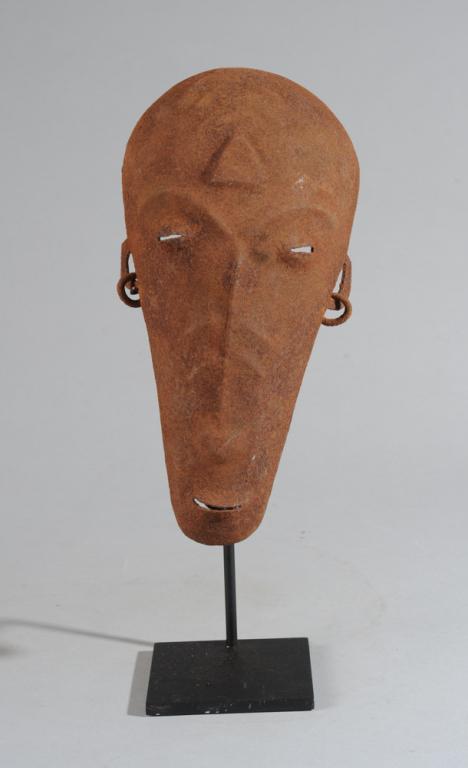 Bamana Iron Mask: Narrow iron mask, the high round forehead with raised triangular and linear marks, half closed eyes, long slender nose and slightly protruding mouth. Small ears with hoop earrings. Bamana or Bambara t