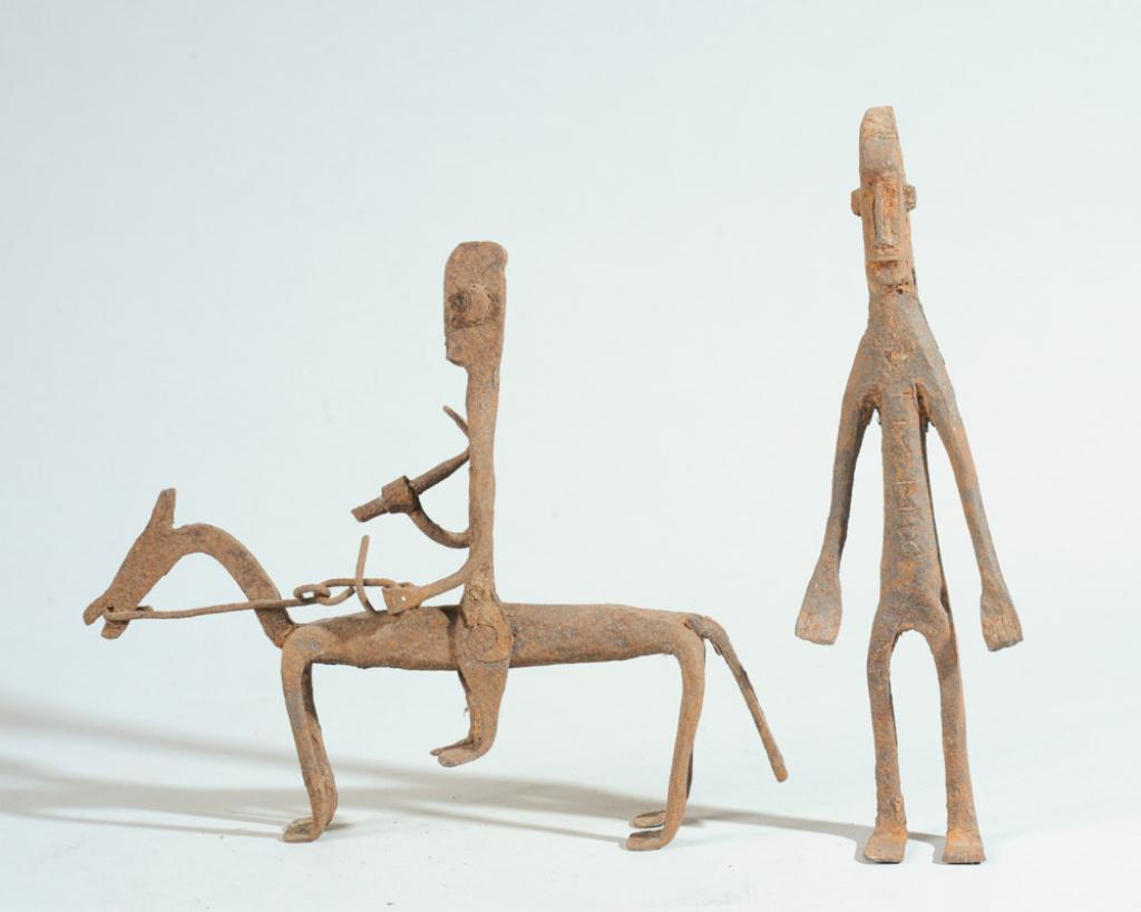Two Dogon or Bamana Iron Figures, Mali: To include an equestrian figure astride horse, carrying hoe or other implement, and a standing figure on custom gallery base. Surface loss to area of base. Figure somewhat top heavy / unstable on base