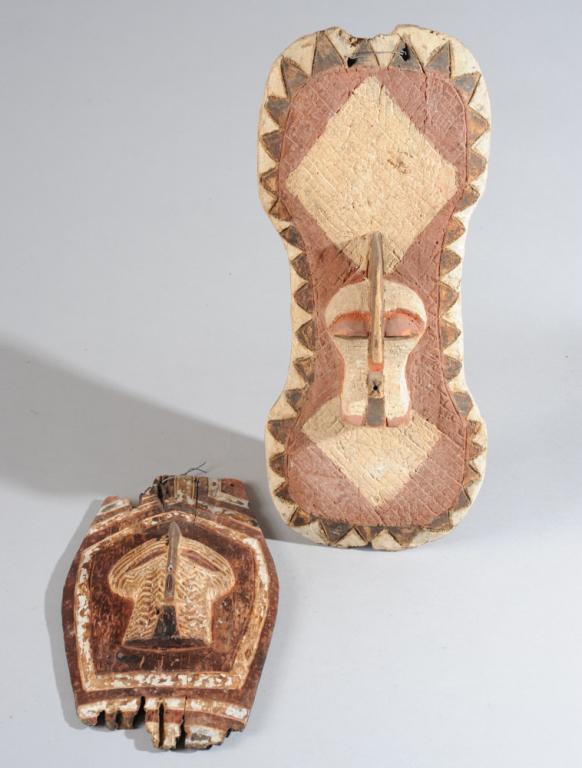 Two Songye Shields or Plaques: Both with central 'kifwebe' mask in relief surrounded by incised and pigmented geometric patterns. Old insect damage to both. The larger, approx. 17' x 7". Provenance: Estate of Thomas McNemar, (1931-