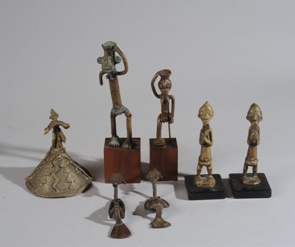 Lot West African Bronze Miniature Figures: Anthropomorphic cast bronze figures, four on gallery stands, including a Baule pair. Also a figural bell and a pair of reclining figures. Damage to leg of tallest figure, loss of one leg to female fig