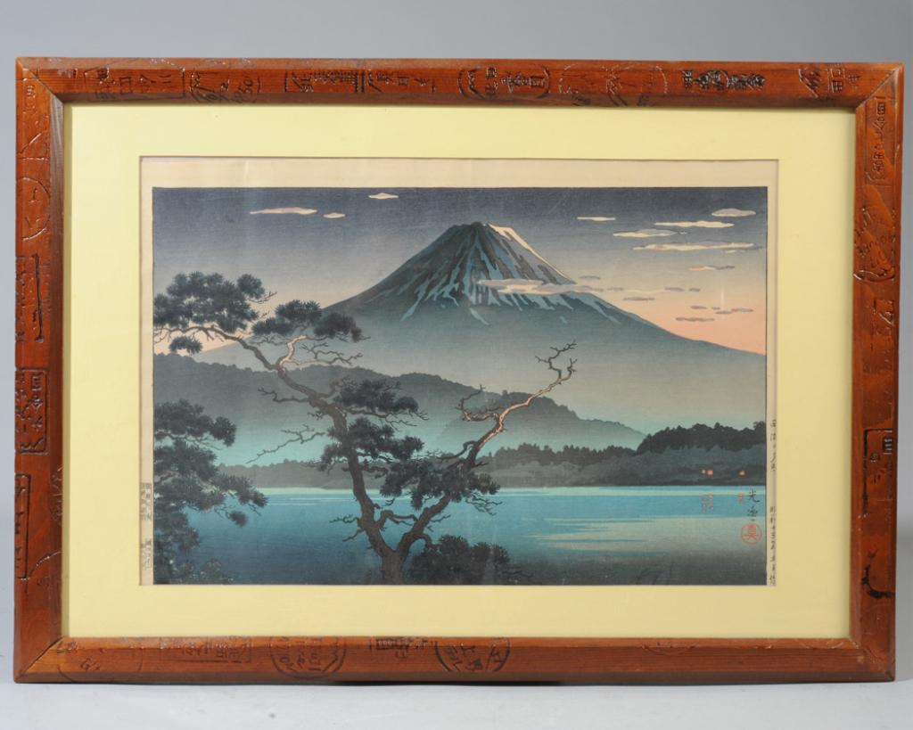 Tsuchiya Koitsu Japanese Woodblock: Evening View of Mt. Fuji from Lake Sai, "Saiko No Yusho" by Tsuchiya Koitsu, (1870-1949). Signed lower right, publishers seal outside left margin. Unusual frame with branded Japanese inscriptions expl