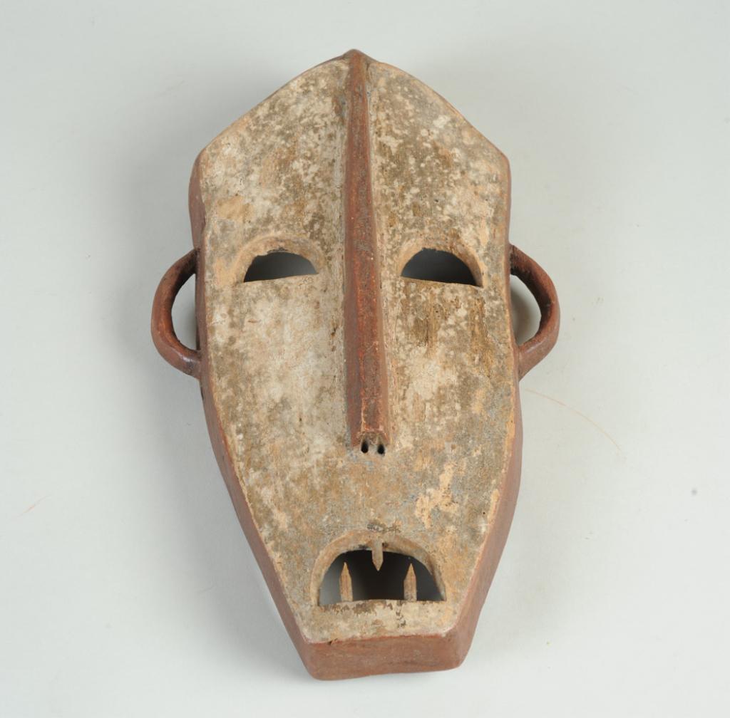 Lega Mask, D. R. Congo: Flattened mask with simplified but expressive features. The facial plane whitened with kaolin and bisected by linear, dark brown nose. The eyes and mouth all semi-circular holes, the mouth with three