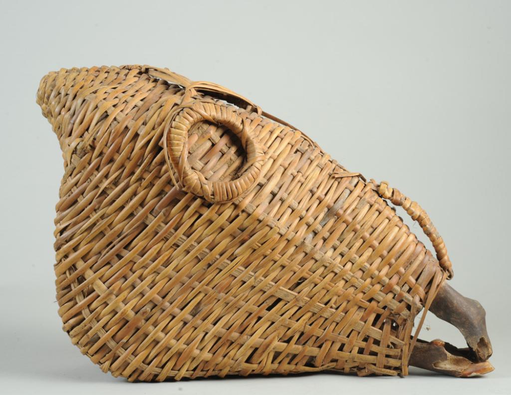 Rattan Wrapped Animal Skull: Zebra or similar skull entirely covered except for the nose in woven cane, with rings where the eyes would be, a woven diamond at the forehead and a handle. Possibly a hunting trophy. Approx. 20 1/2" 