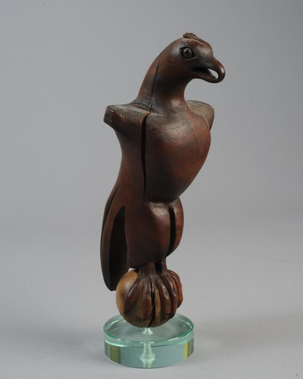 Folk Art Carved Hardwood Eagle: Folk carved eagle with truncated wings, perched on ball. Lucite or glass base added later. Approx. 13" total height. Provenance: Estate of Cayce Odom of Charlottesville, VA.