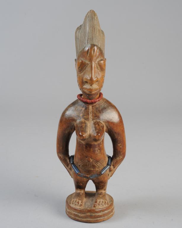 Yoruba Ibeji Twin Figure: Carved wooden 'twin' figure, appears to be the work of the Igbuke compound of carvers, Oyo, with complex, vertical coiffure, bulging eyes with lashes, somewhat pointed ears, typical facial and body sc