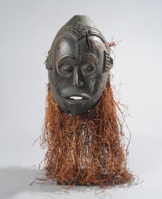 Idoma Mask, Nigeria: The eyes set in large hollows, giving a startled look, and with slender nose, open mouth, facial scarification, and raffia collar. On custom gallery stand. Mask, (excluding raffia,) approx. 13" X 8 1/