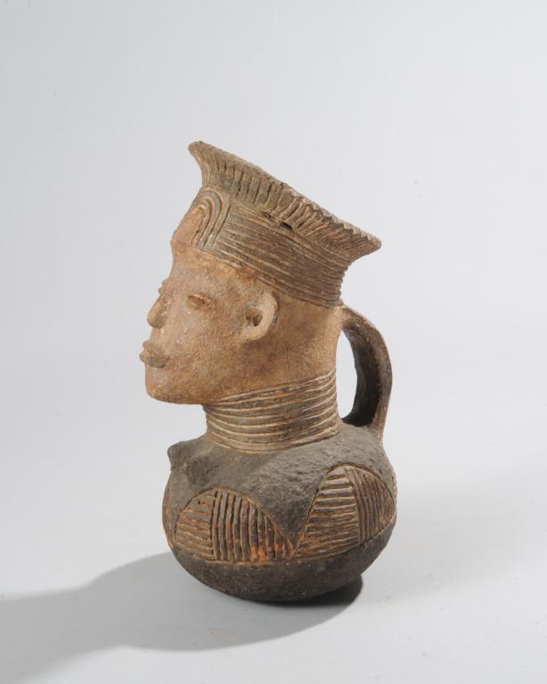 Mangbetu Palm Wine Jar: Terracotta palm wine vessel in the form of an ideal Mangbetu woman, with traditional elongated head and high flaring crown of braids. Democratic Republic of Congo. Approx. 11 3/4" H. Provenance: Estat