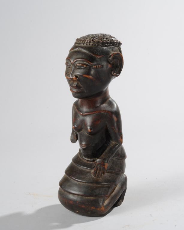 African Carved Wood Statue: Naturalistic depiction of a kneeling figure with elaborately braided hair, relief carved keloid scars at the temples. Tribe and country of origin not identified. Approx. 10" H. Provenance: Estate of T