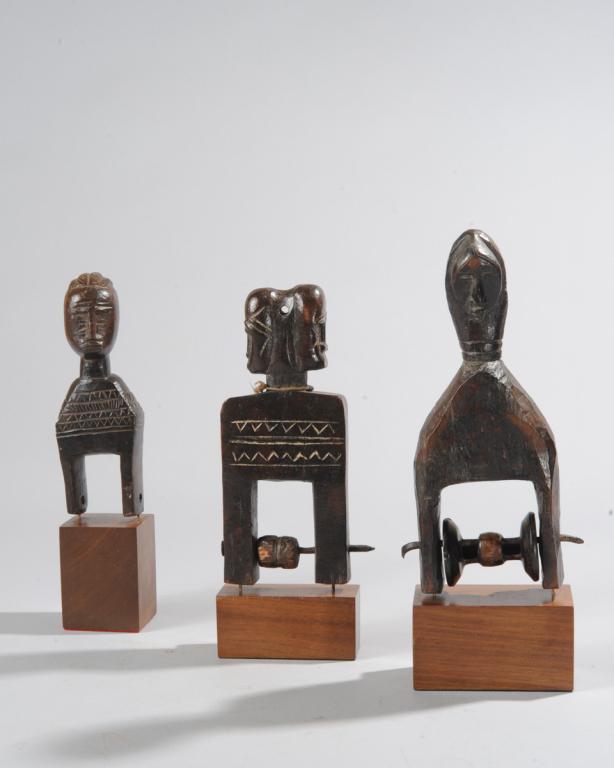 Three West African Heddle Pulleys: Likely Baule or Guro, Ivory Coast. Figurative finials, one with Janus heads. All on custom gallery stands. The tallest, approx. 10 3/4" total height. Provenance: Estate of Thomas McNemar, (1931-2020.)