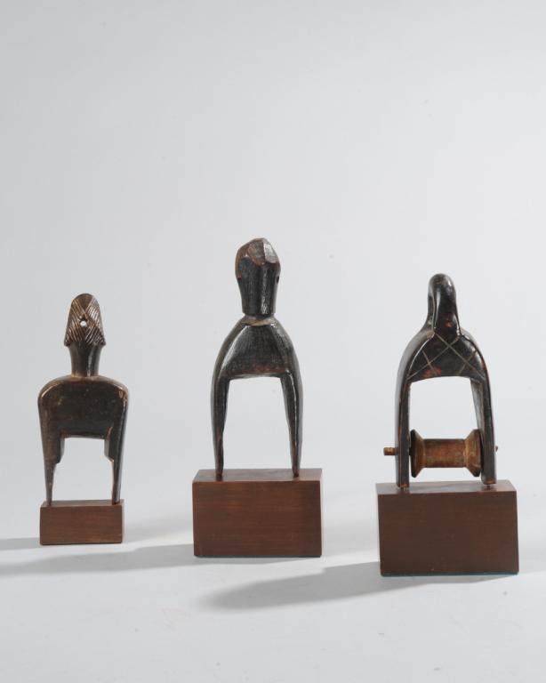Three West African Heddle Pulleys: Of abstract form, one with large loop finial. All on custom gallery stands. Tallest, approx. 8 1/2" total height. Provenance: Estate of Thomas McNemar, (1931-2020.) McNemar lived and collected through
