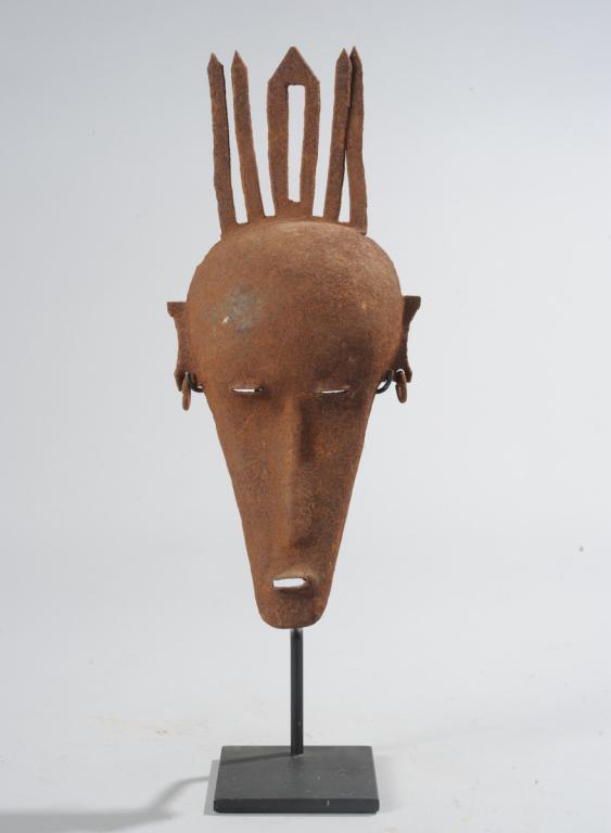 Bamana Iron Mask, Mali: With a row of horns rising above the wide, round forehead, withdowncast eyes, long slender nose, small mouth, earrings. Oxidized surface. On custom gallery stand. Mask, approx. 11 1/4" x 5". Provenanc