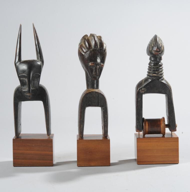 Three African Heddle Pulleys, Ivory Coast: To include a Senufo pulley with avian head atop long ringed neck, old staple repair; a horned Djimini pulley, and a janiform Baule or Guro pulley, the opposing heads with differing coiffures. All on c