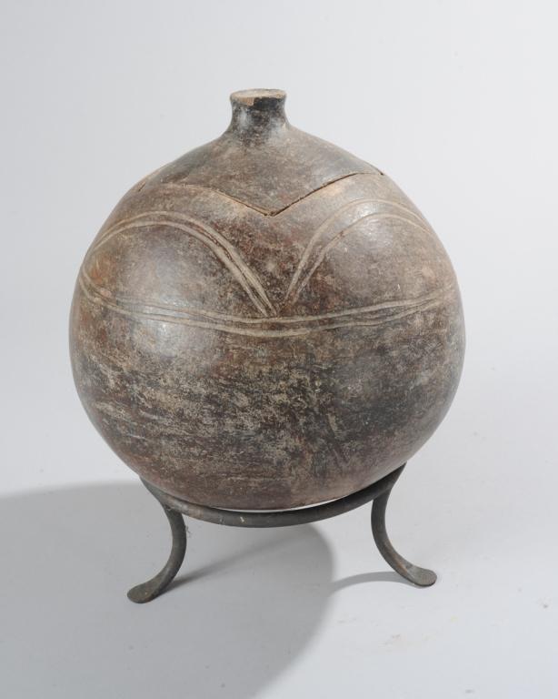 Lobi Pot: Spherical gray pottery vessel, the conforming lid with stubby handle, the sides embellished with curving incised lines. Lobi artist, Ivory Coast or Burkina Faso. On iron stand. Pot, approx. 11" H, 9 1