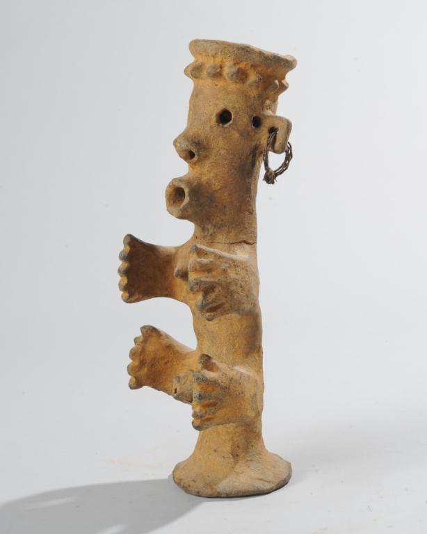African Clay Figure / Receptacle: Crowned male figure with receptacle in the top of the head and protruding, tube-like mouth, the body with truncated arms and legs reaching forward, with small breasts and prominent phallus. Tribe and