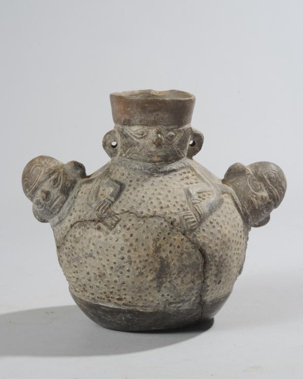 Chimu Blackware Anthropomorphic Jar: Dark gray earthenware jar with three human figures, the central and largest of these serving as the vessel's mouth, all three linking arms across the stippled body of the jar. Restorations, chips. est