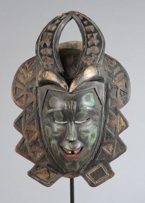 Guro Zamble Mask: The delicately carved human face with three vertical raised marks on forehead, and relief carved scarification at temples, incised marks to cheeks. the eyes downcast, the mouth open and set with squar
