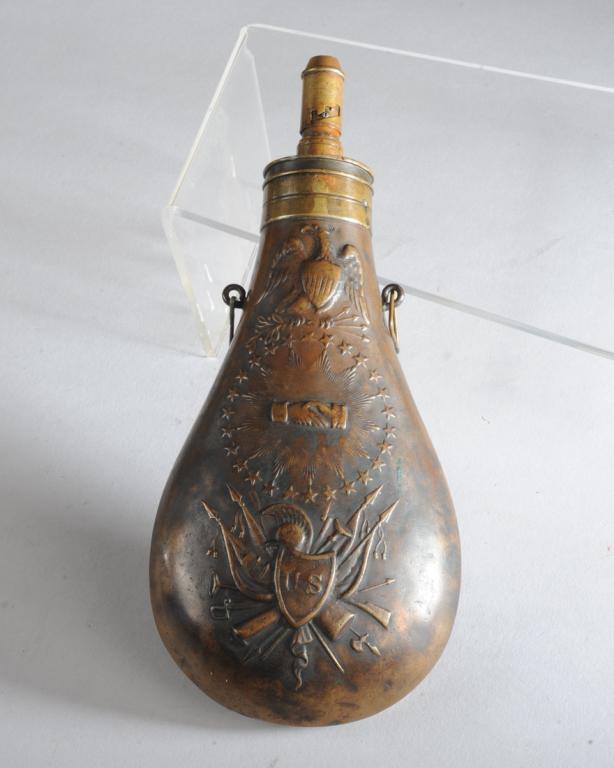 N. P. Ames 1838 'Peace' Powder Flask: Stamped 1838 and N. P. Ames, 9" long, both sides with repousse left-facing eagle above clasped hands surrounded by a circle of 26 stars above a shield with "U.S." over crossed flags and weapons. One s