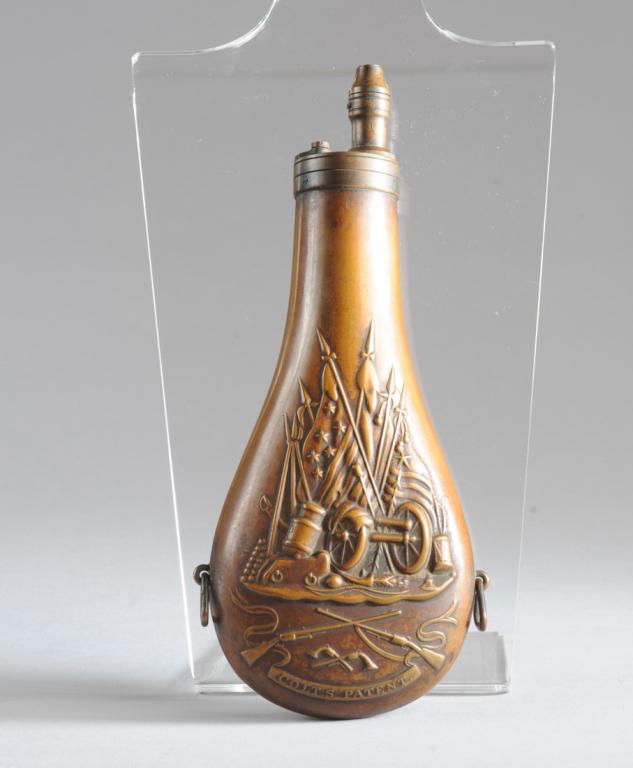 Colt 9" Revolver Powder Flask: Colt powder flask with relief stand of arms images on both sides showing cannon, balls, spears, and Texas and US flags above crossed firearms with "Colt's Patent" on banner below. Slide lid to ball co
