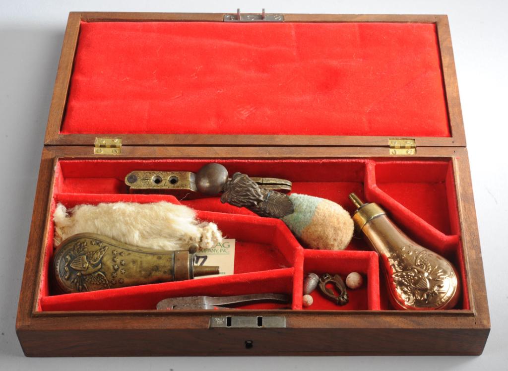 Pistol Box with Accessories: Two double cavity bullet molds, small caliber, one small powder flask, second brass powder flask, two cleaning devices. In wood box. 12 1/4" x 6" x 2". Provenance: The estate of Fred France.